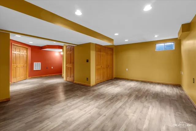 a view of an empty room with wooden floor and closet