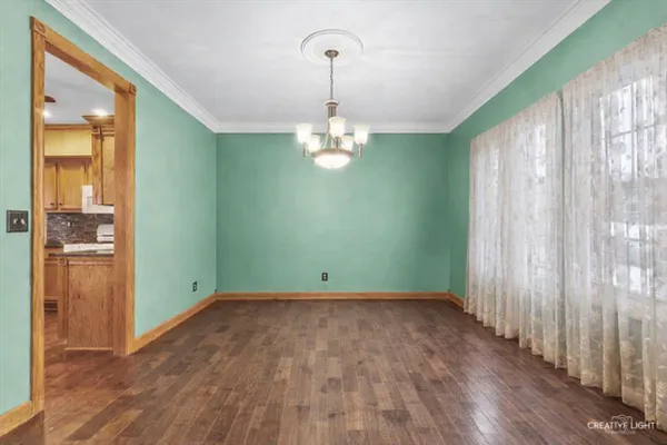 a view of an empty room with wooden floor fire place and a window