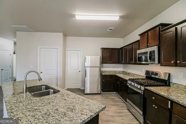a kitchen with stainless steel appliances granite countertop a sink stove and refrigerator