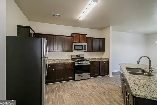 a kitchen with stainless steel appliances granite countertop a refrigerator stove microwave and sink