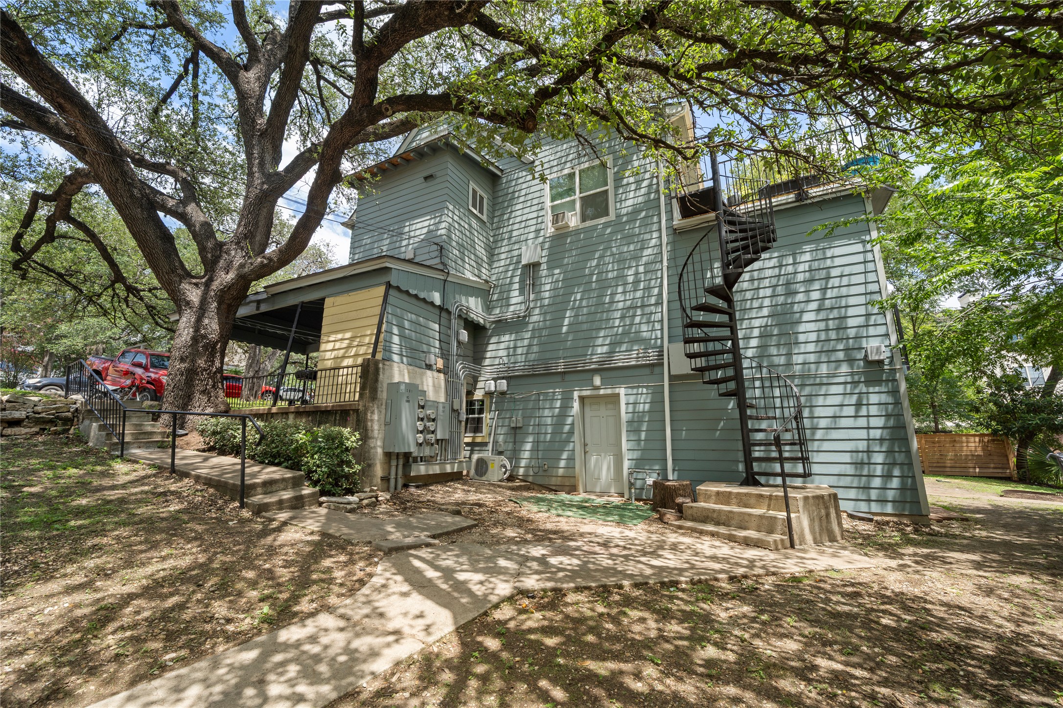 201 West 31st Street, Unit E Austin, TX 78705 - Photo 12 of 16 Mature trees shade the exterior of this inviting residence, featuring a spiral staircase for elevated access.