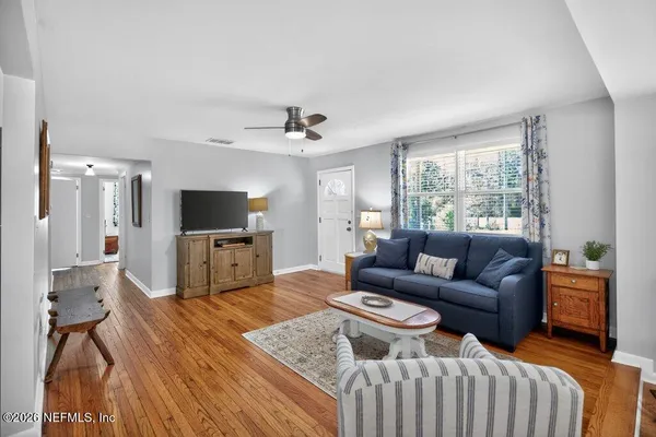 a white kitchen with stainless steel appliances granite countertop a sink dishwasher a stove and a refrigerator with wooden floor