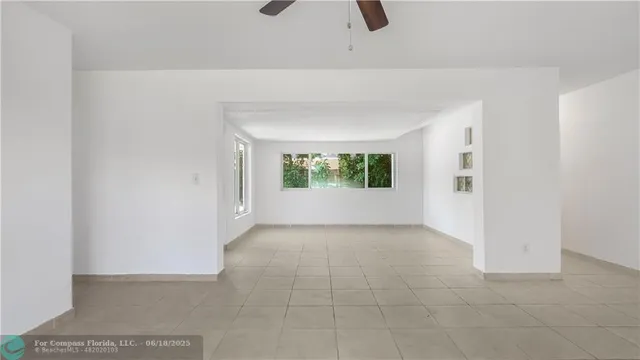 an empty room with windows and ceiling fan