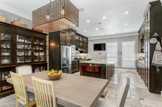 a kitchen with stainless steel appliances kitchen island granite countertop a refrigerator a stove a sink a dining table and chairs with wooden floor