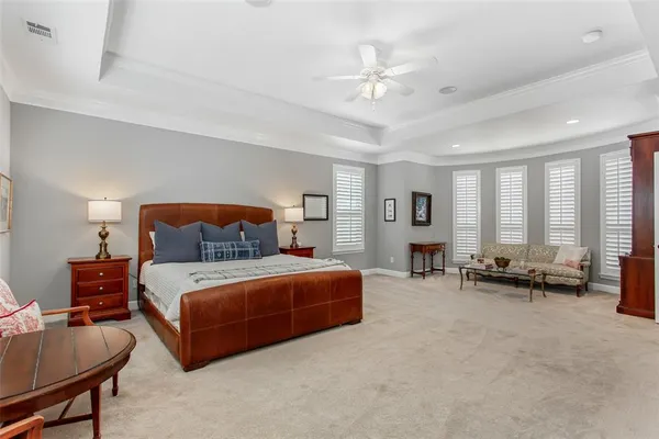a spacious bedroom with a bed a couch and large windows