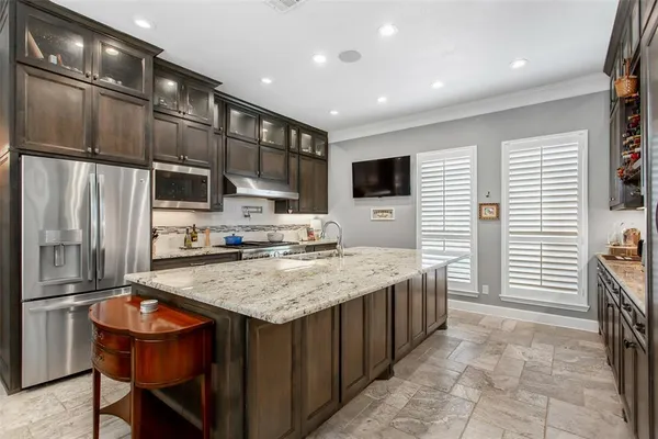 a kitchen with stainless steel appliances granite countertop a table chairs sink refrigerator and microwave