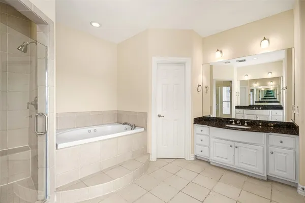 a spacious bathroom with a granite countertop sink a mirror a bathtub and a shower