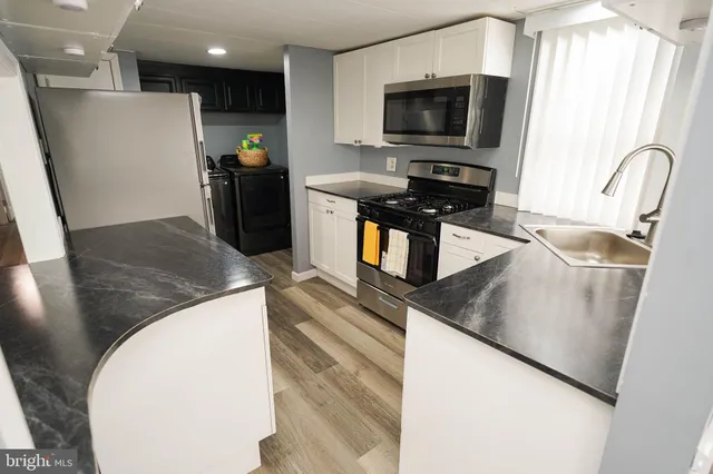 a kitchen with stainless steel appliances granite countertop a sink a microwave a refrigerator and a stove