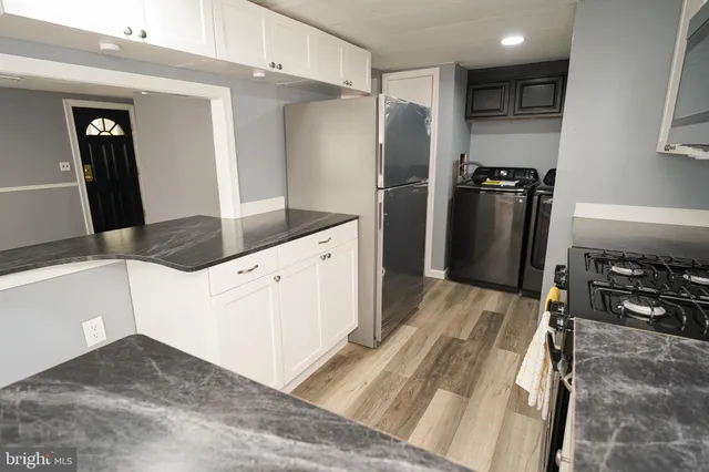 a kitchen with stainless steel appliances kitchen island granite countertop a refrigerator and a sink