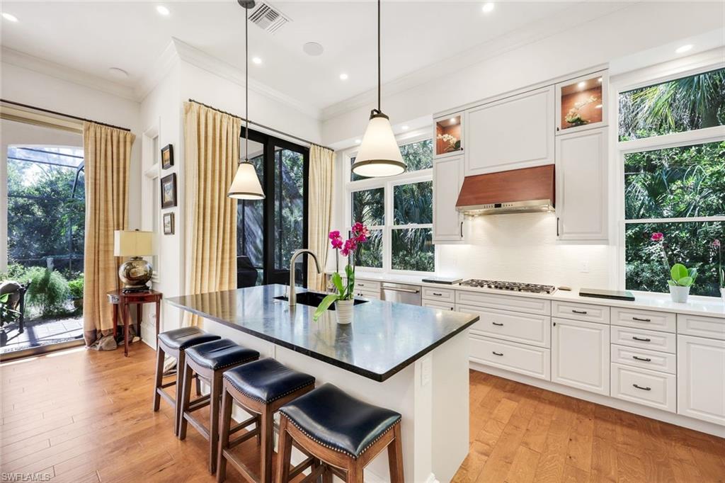 18051 Lagos Way Naples, FL 34110 - Photo 8 of 35 a kitchen with granite countertop a stove a dining table and chairs with wooden floor