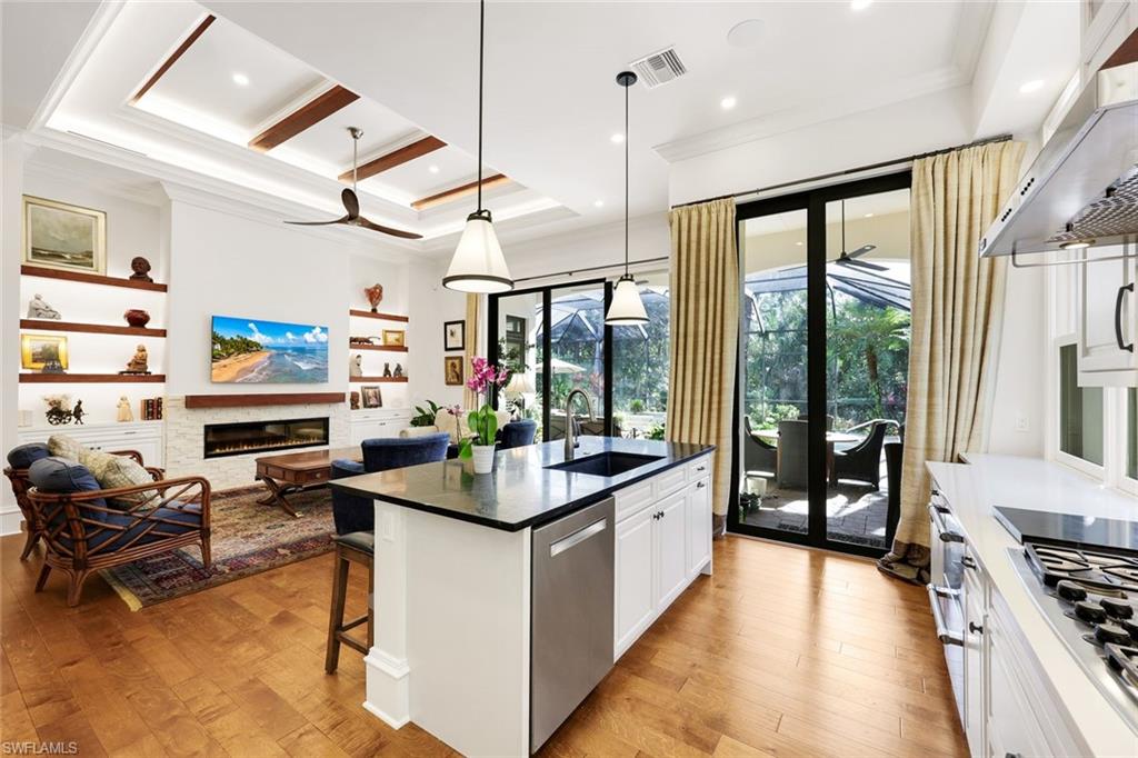 18051 Lagos Way Naples, FL 34110 - Photo 9 of 35 a kitchen with stainless steel appliances kitchen island granite countertop a stove and white cabinets