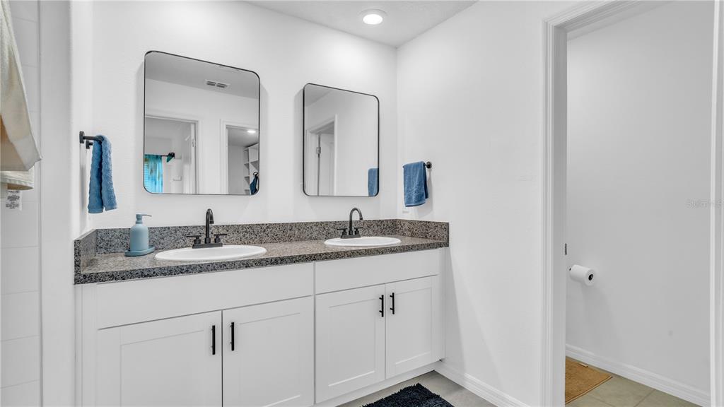 1841 Crinkle Leaf Court Ruskin, FL 33570 - Photo 24 of 35 a bathroom with a granite countertop sink double and mirror