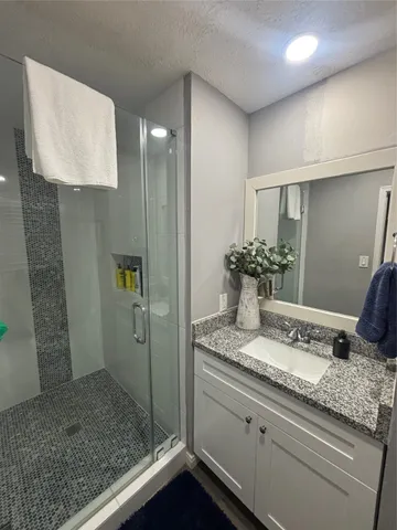 a bathroom with a granite countertop sink a mirror and shower