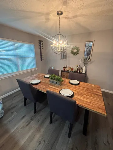 a dining room with wooden floor a chandelier a wooden table and chairs