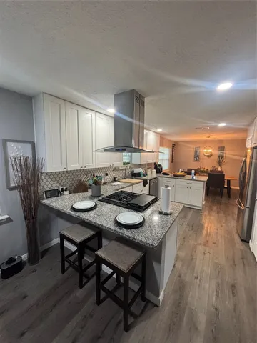a kitchen with stainless steel appliances granite countertop a table chairs sink and cabinets