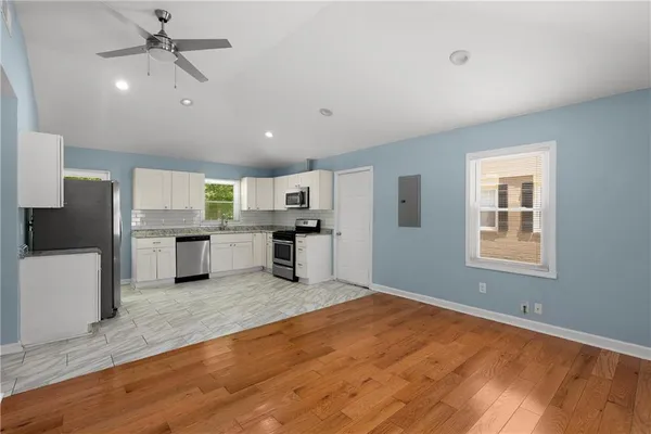 a large white kitchen with kitchen island a stove a sink dishwasher and a refrigerator with wooden floor