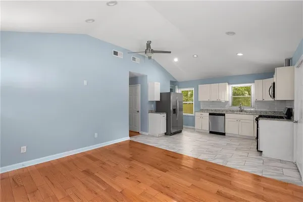 a view of a kitchen with a refrigerator a stove top oven and cabinets