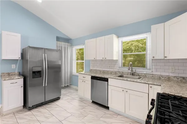 a kitchen with stainless steel appliances granite countertop a sink stove and refrigerator