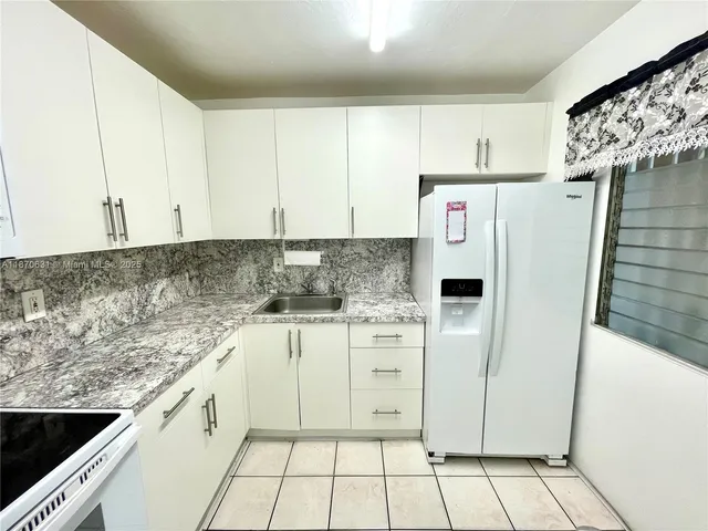 a kitchen with stainless steel appliances granite countertop a refrigerator sink and white cabinets