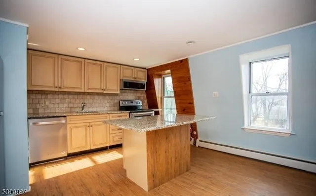 a kitchen with granite countertop white cabinets and wooden floor