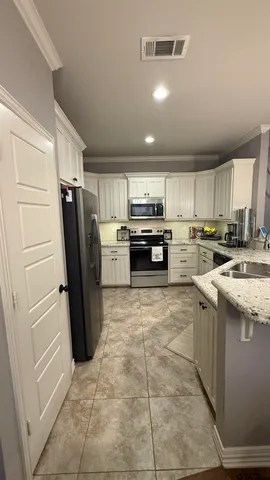 a kitchen with granite countertop a refrigerator and a stove top oven