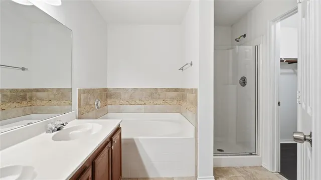 a bathroom with a tub sink vanity and granite