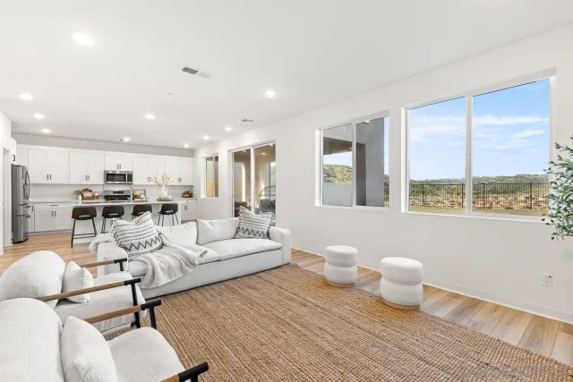 a kitchen with stainless steel appliances kitchen island granite countertop a dining table chairs and a refrigerator