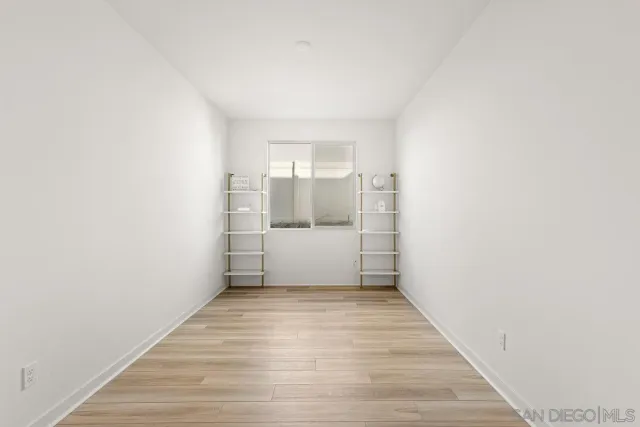 a view of a hallway to room with wooden floor and windows