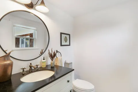 a bathroom with a granite countertop toilet a sink and mirror