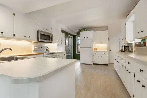 a kitchen with stainless steel appliances a refrigerator sink and white cabinets