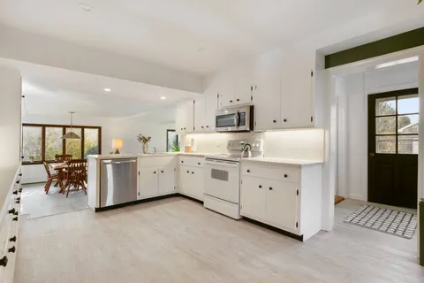 a kitchen with white cabinets and white appliances