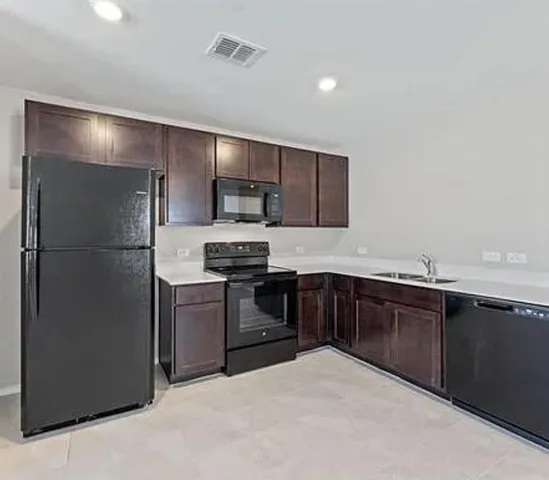 a view of kitchen with refrigerator and a stove top oven