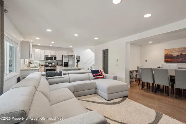 a living room with furniture kitchen view and a large window