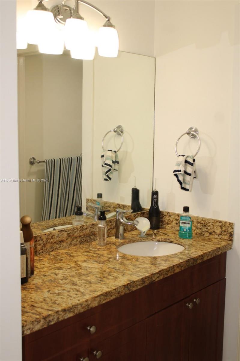 1221 Southwest 122nd Avenue, Unit 401 Miami, FL 33184 - Photo 15 of 22 a bathroom with a granite countertop sink and a mirror
