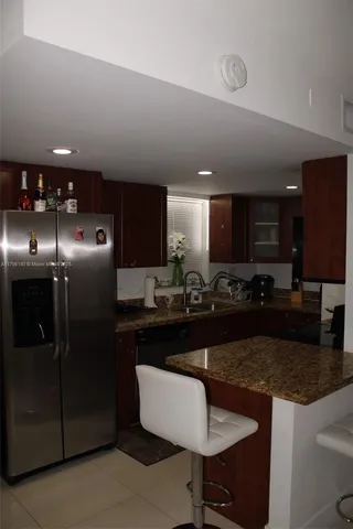 a kitchen with stainless steel appliances granite countertop a sink a stove a refrigerator a microwave a dining table and chairs