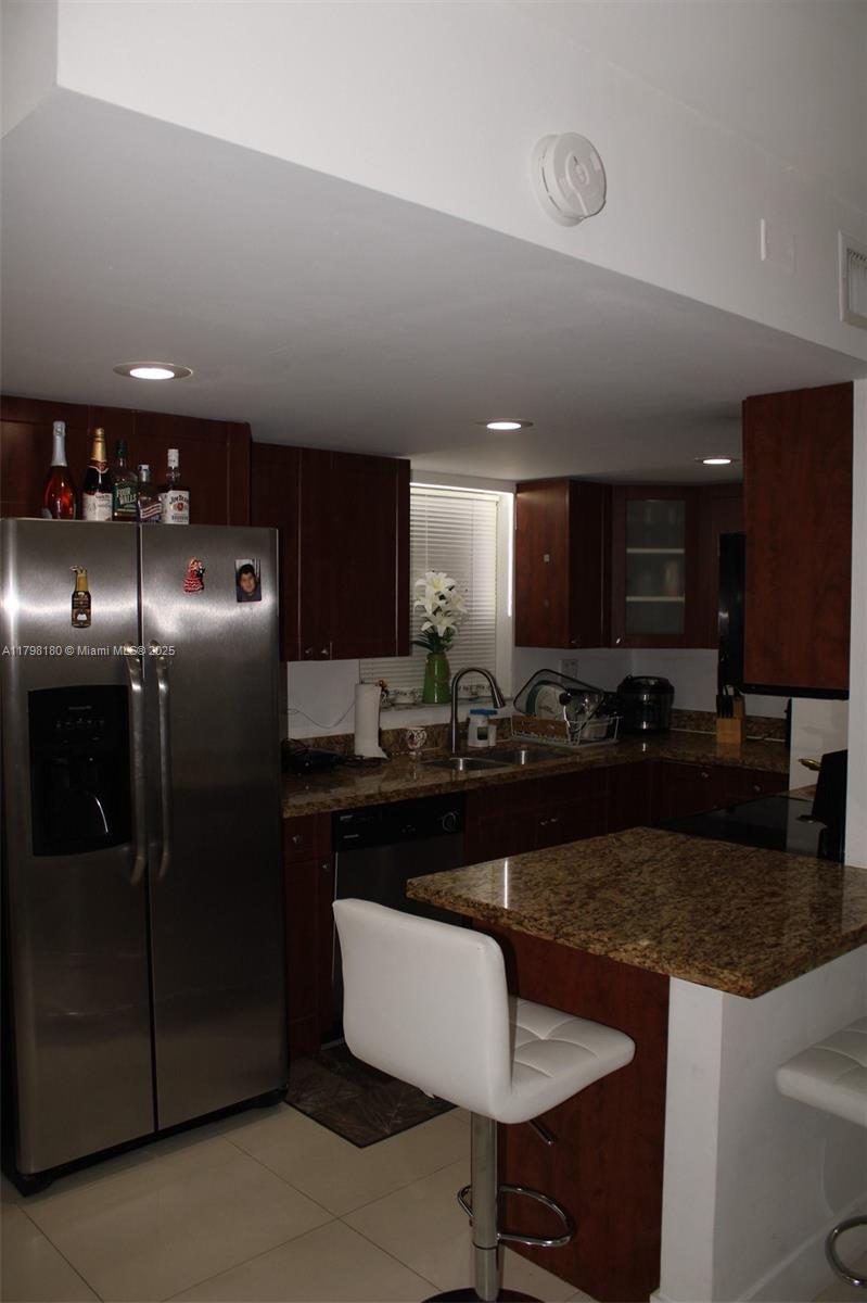 1221 Southwest 122nd Avenue, Unit 401 Miami, FL 33184 - Photo 8 of 22 a kitchen with stainless steel appliances granite countertop a sink a stove a refrigerator a microwave a dining table and chairs