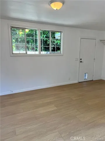 a view of an empty room with wooden floor and windows