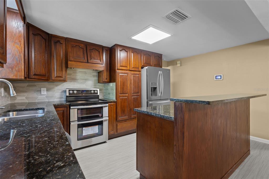 1908 West Fern Street Tampa, FL 33604 - Photo 9 of 47 a kitchen with granite countertop a refrigerator and a stove top oven