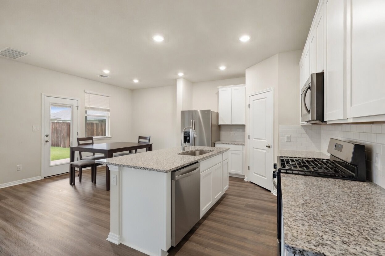 129 Greenway Drive Georgetown, TX 78628 - Photo 2 of 22 a kitchen with stainless steel appliances a stove top oven a sink a refrigerator white cabinets and wooden floor