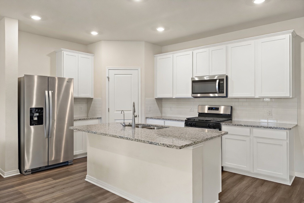 129 Greenway Drive Georgetown, TX 78628 - Photo 3 of 22 a kitchen with stainless steel appliances granite countertop a refrigerator a sink a stove a microwave and wooden cabinets