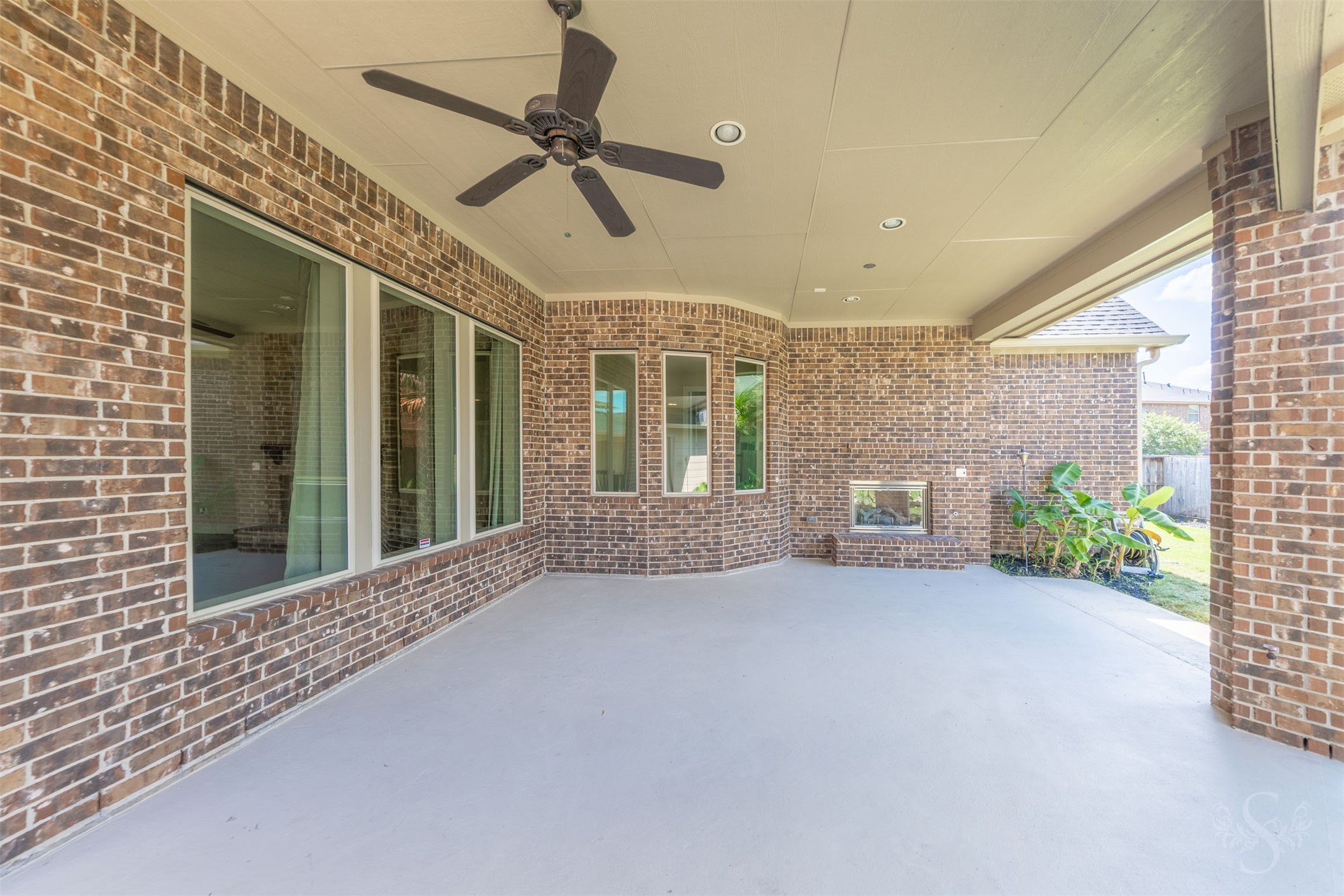 5803 Mustang Ridge Lane Fulshear, TX 77441 - Photo 41 of 48 Impressive covered patio is designed for year-round outdoor living with recessed lighting, ceiling fan and a stunning brick fireplace that creates a warm gathering space. Curved architectural details and multiple seating areas add character and flexibility for entertaining outdoors.