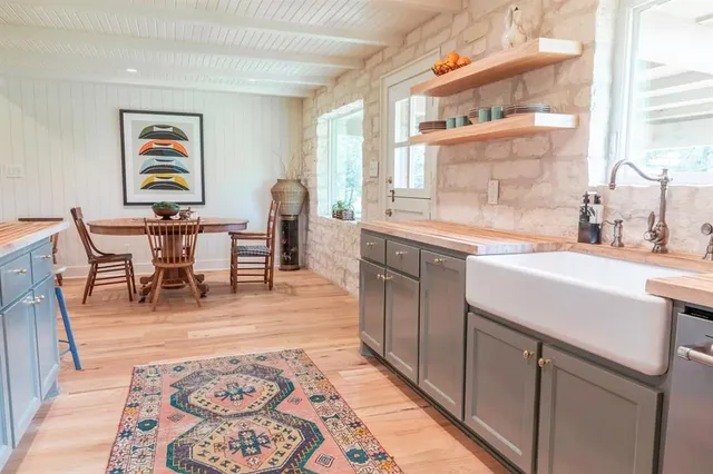 a living room with stainless steel appliances granite countertop a couch and a dining table with wooden floor