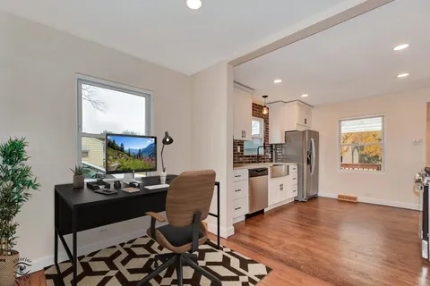 a kitchen with stainless steel appliances a stove a sink a refrigerator and a dining table with wooden floor