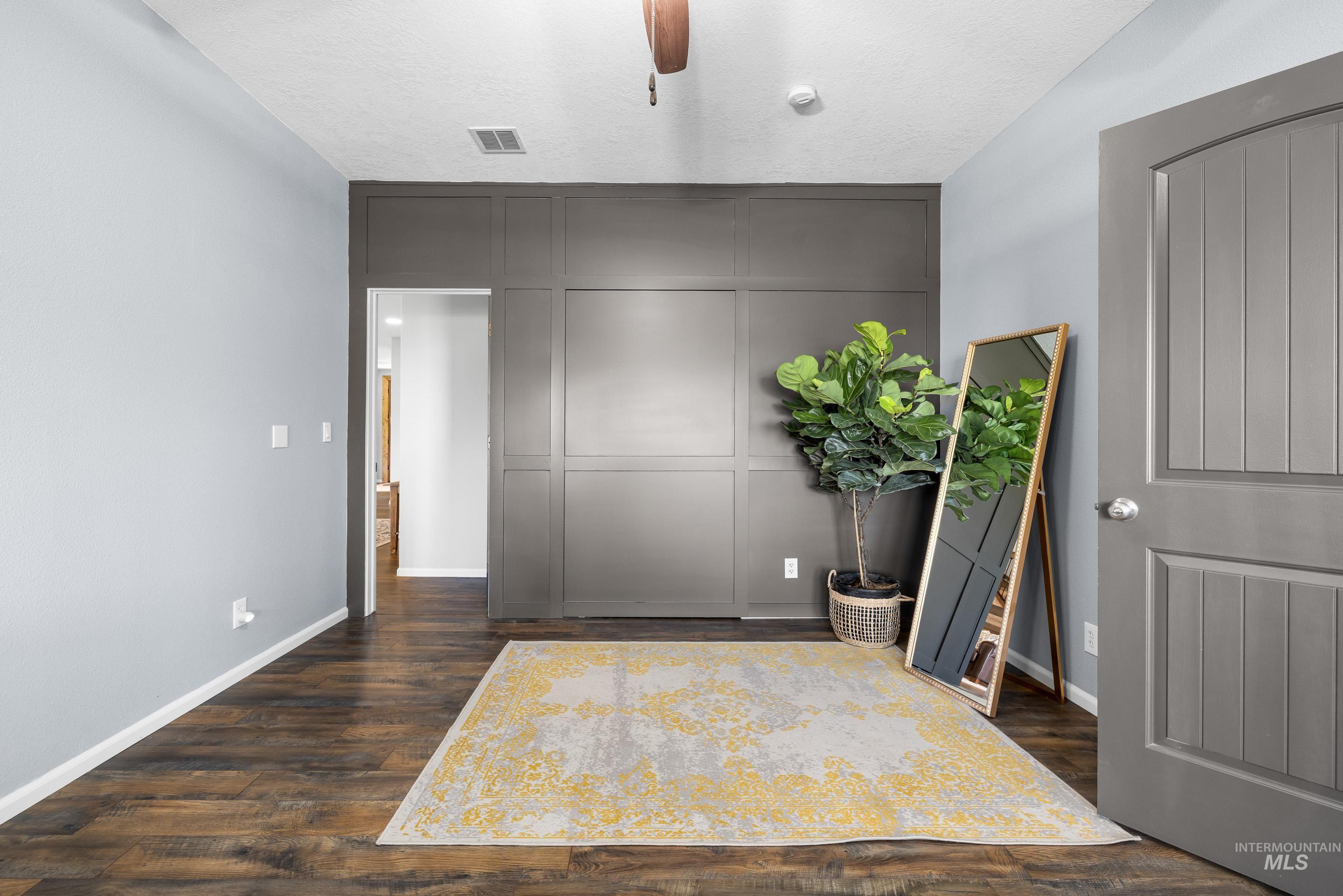 14119 Silver Ridge Road Caldwell, ID 83607 - Photo 21 of 50 Bedroom with a decorative wall, dark wood finished floors, a textured ceiling, a closet, and ceiling fan