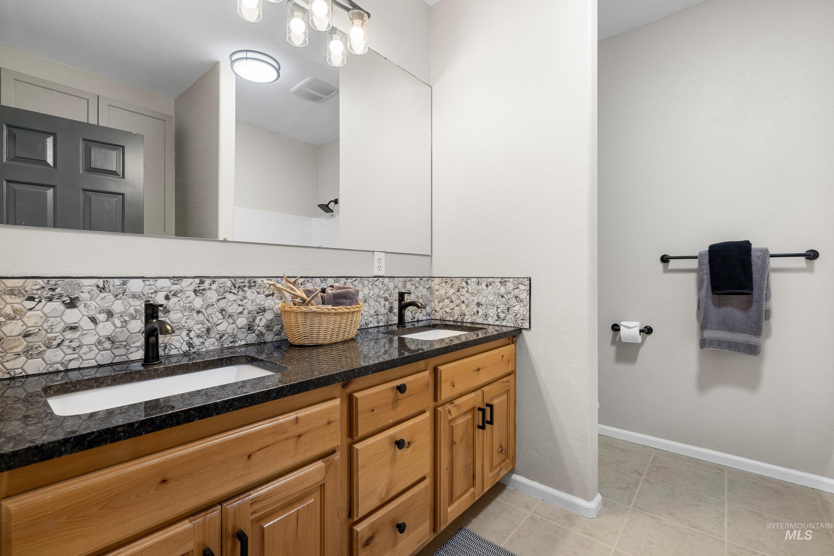 14119 Silver Ridge Road Caldwell, ID 83607 - Photo 27 of 50 Bathroom with backsplash, light tile patterned floors, and double vanity