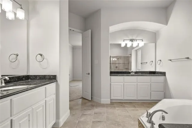 a spacious bathroom with a granite countertop sink a mirror and a shower