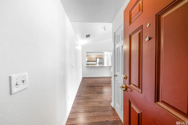 a view of a hallway with wooden floor and a bathroom