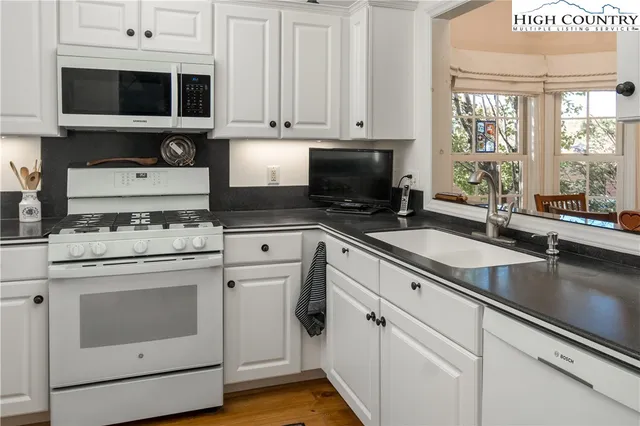 a kitchen with stainless steel appliances granite countertop a stove a sink and a microwave