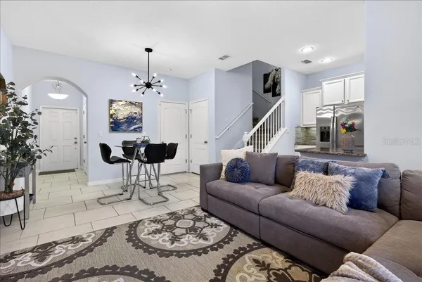 a living room with furniture a dining table a rug a chandelier and a chandelier