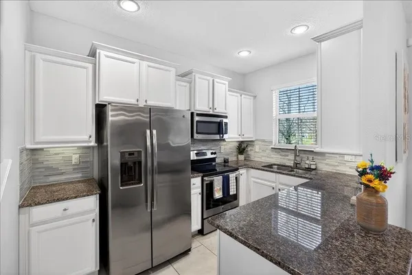 a kitchen with stainless steel appliances granite countertop a refrigerator a stove a sink a dining table and chairs